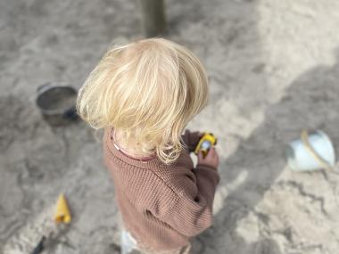 Lille barn leger i sandkassen.